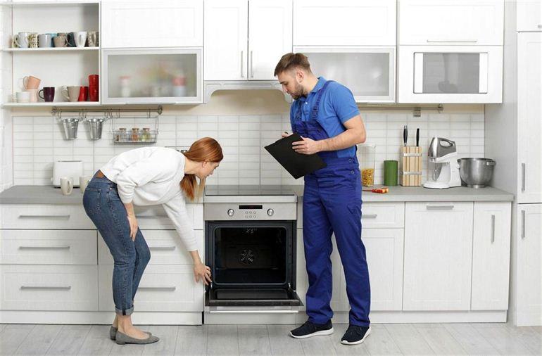 woman shows her oven problem to a mechanic