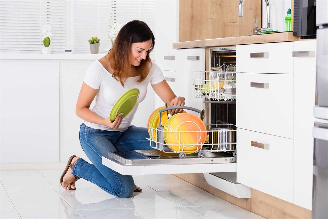 a woman putting plates into dishwasher in the kitchen