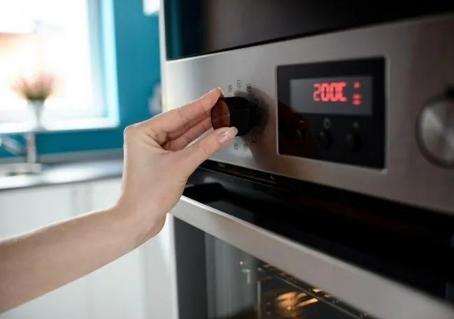 baking-or-broiling-not working-correctly a hand turns stove temperature to 200C