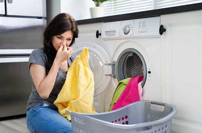 a woman with dirty laundry near washing machine