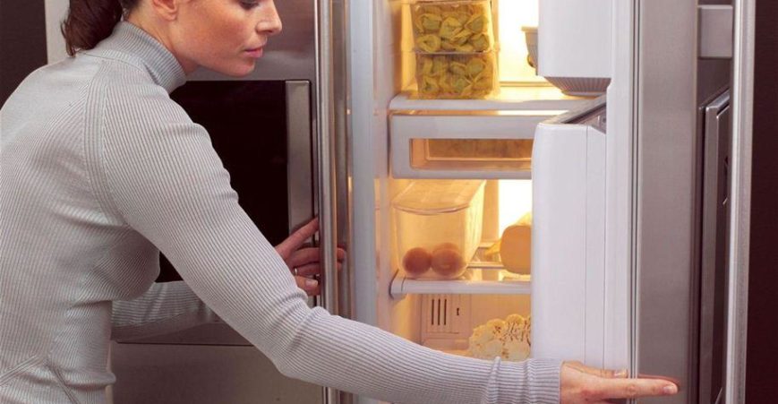 a woman opens a fridge