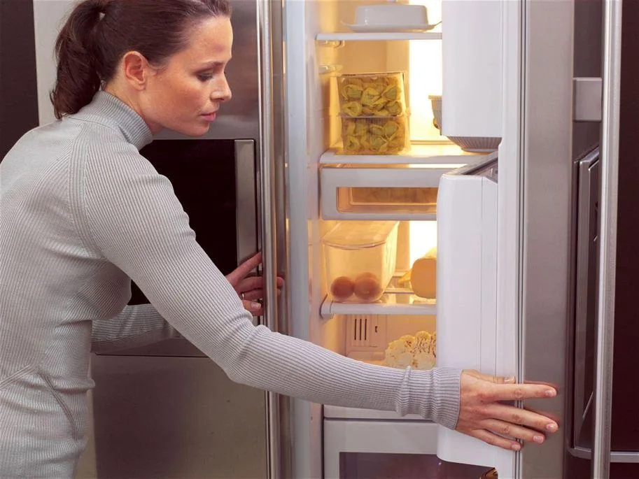 a woman opens a fridge