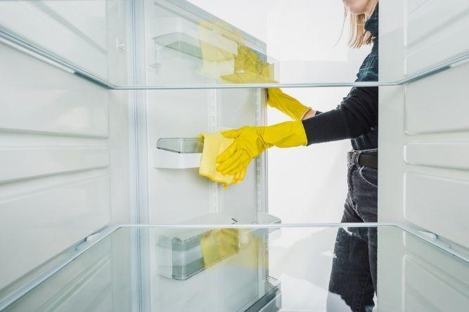 woman cleaning the fridge in yellow gloves
