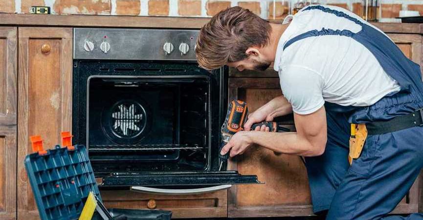 a mechanic is repairing an oven