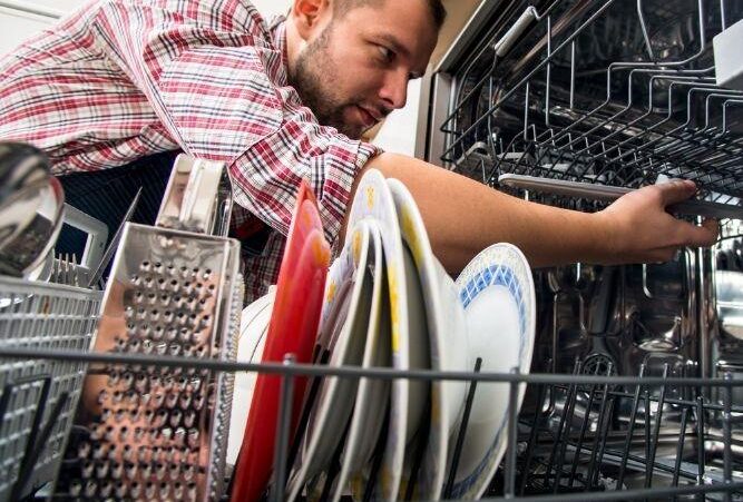 a close up image of a man fixing a dishwasher