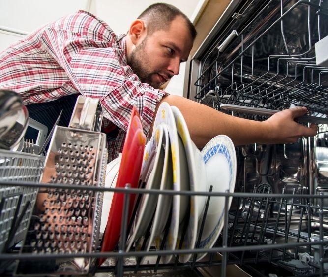 a close up image of a man fixing a dishwasher