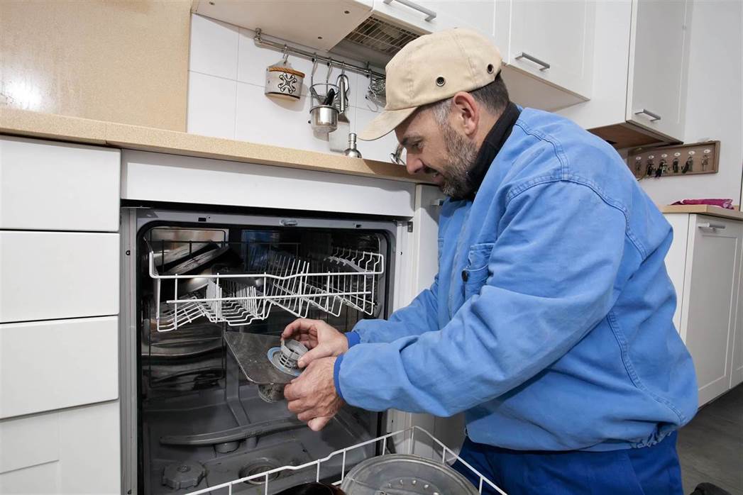 a man repairing dishwasher on the kitchen